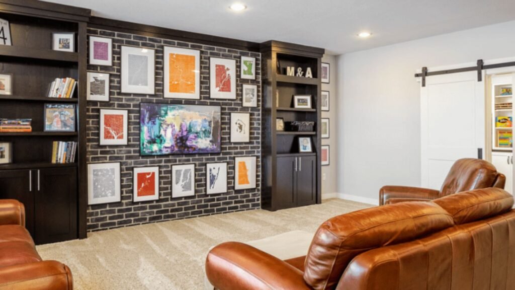 Finished basement media room with leather sofas, black brick accent wall, built-in shelves, and TV impacting basement finishing cost budgets.