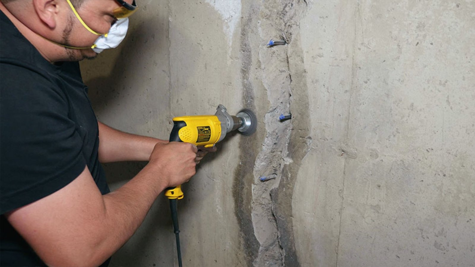 Contractor grinding concrete wall crack before epoxy injection repair to fix basement wall leaks.