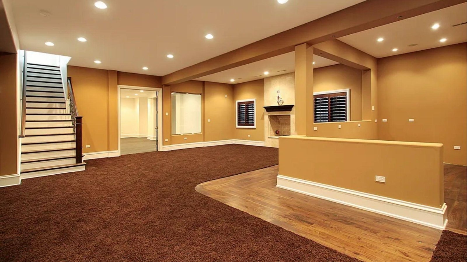 Spacious finished basement with brown carpet, wood flooring, staircase, and fireplace impacting mid-range basement finishing cost estimates.