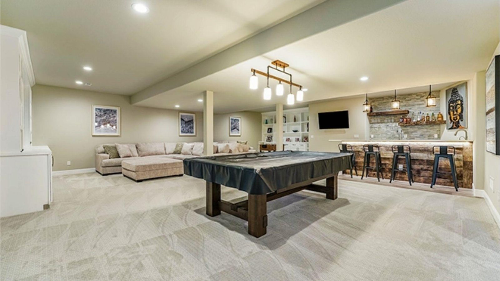 Modern finished basement with pool table, sectional sofa, rustic bar, and recessed lighting affecting overall basement finishing cost.
